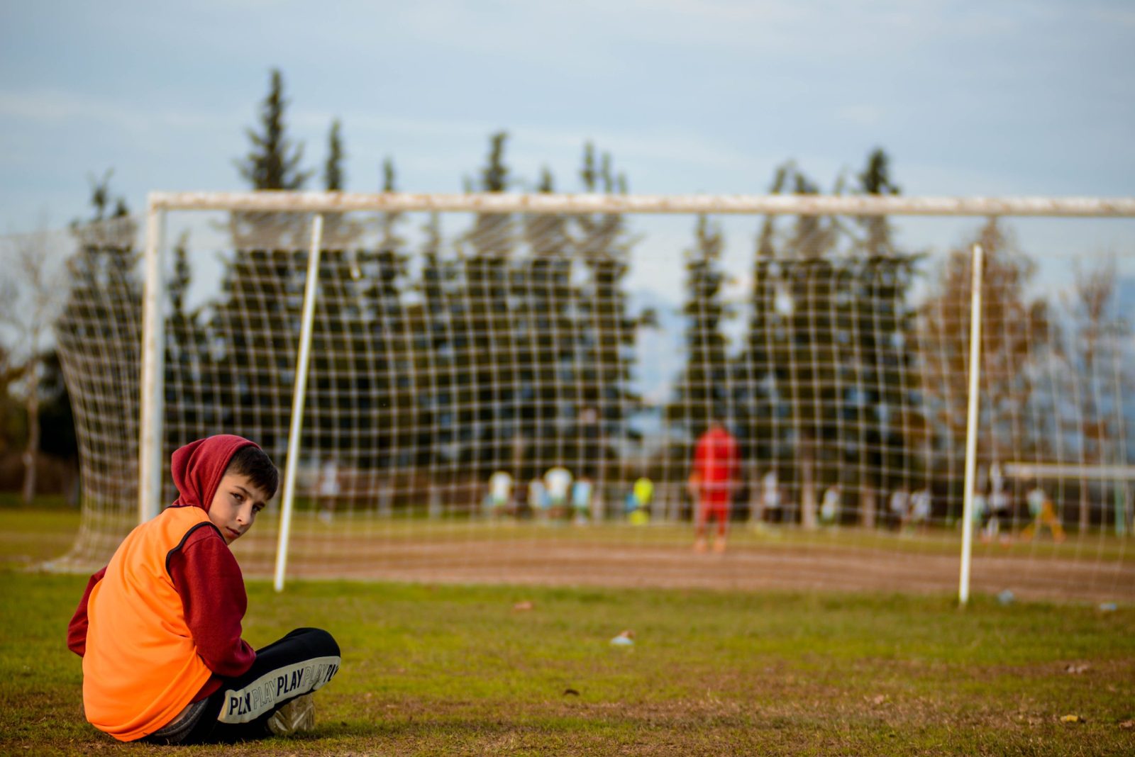 Young player sitting at the side of the pitch during training, nutrition for a 10-year-old footballer